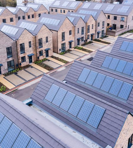 Aerial view of rows of energy efficient new build modular terraced houses in the UK with characterless design and in built rooftop solar panels for first time buyers